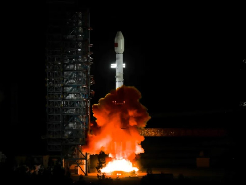 A Long March 3B rocket lifts off from the Xichang Satellite Launch Center at night, sending the Tianlian-2 (05) data relay satellite into orbit. Bright flames and smoke billow from the rocket’s base as it ascends past the illuminated launch tower.