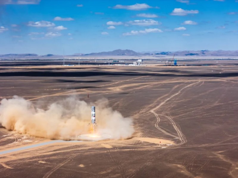 Sand and exhaust billow out from a desert landing pad as the Zhuque-3 rocket test article makes a powered descent.